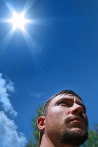 A man standing with the sun shining intensely in the background.