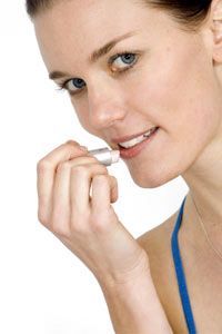 A stunning young woman applying lipstick against a white background
