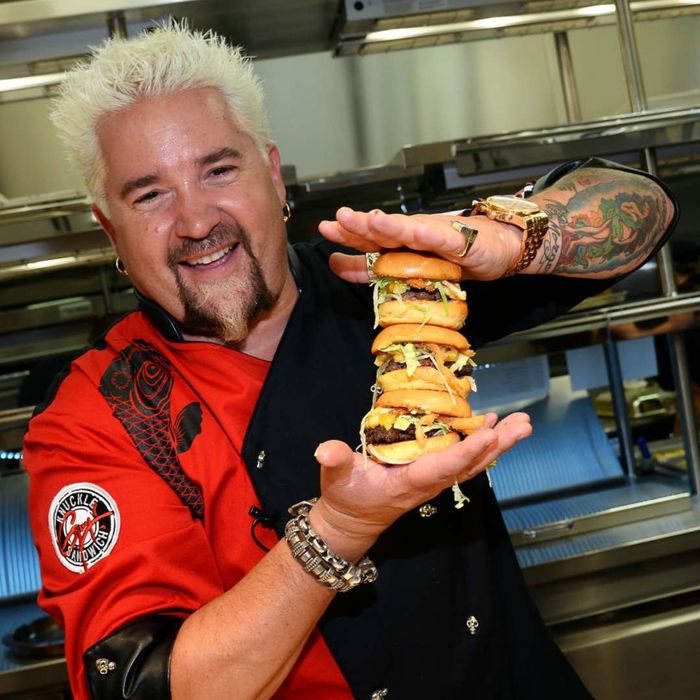 Photo of Guy Fieri holding a pile of cheeseburgers