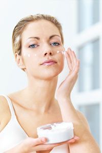 A woman gently applying facial moisturizer