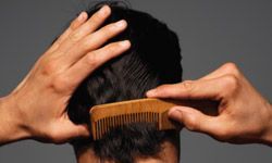 Man with dark hair styling his hair back