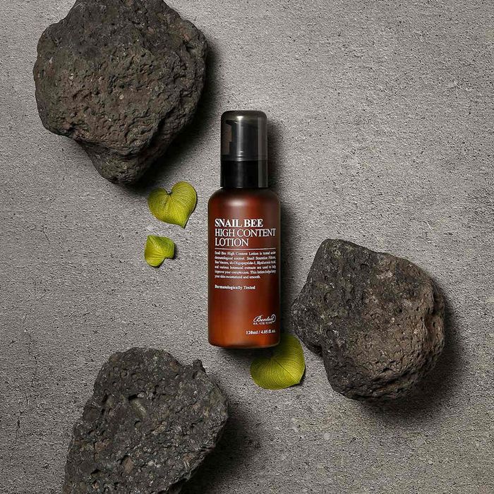 Bottle of healing lotion surrounded by rocks.