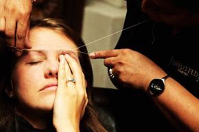 A woman undergoes eyebrow threading during a fashion event in London.