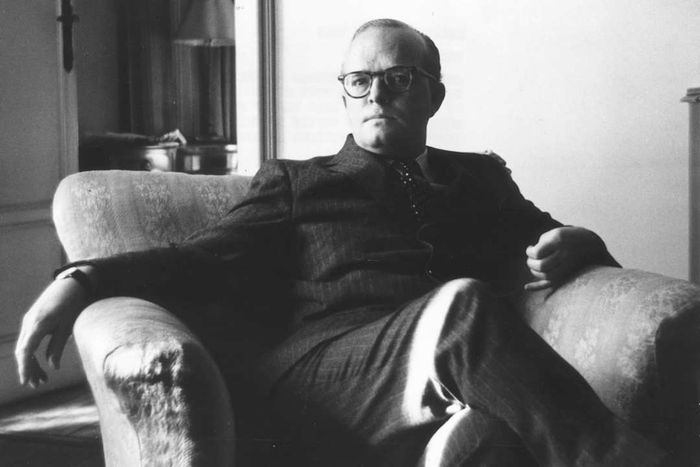 Truman Capote seated in a chair.