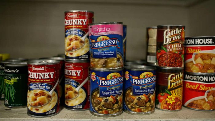 Cans of soup neatly arranged on a shelf.