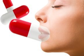 A young woman's lips alongside medication capsules.