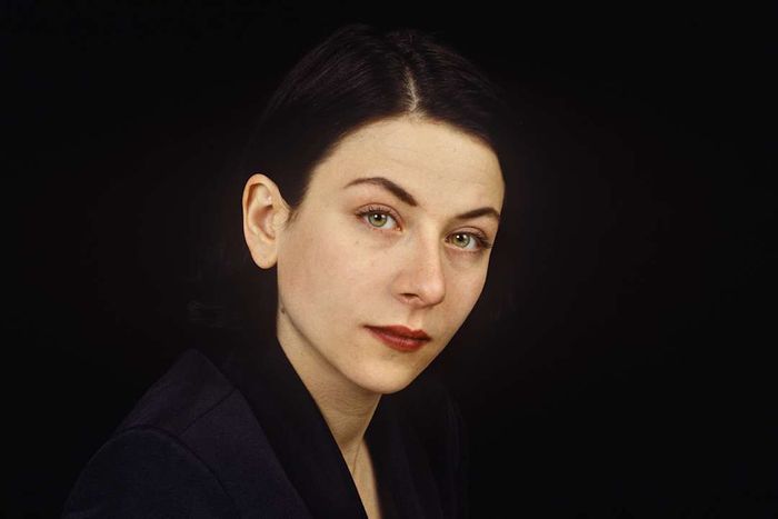 Donna Tartt, gazing directly into the camera with a dark background.