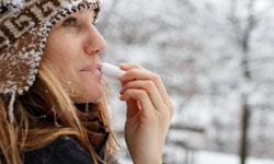 Woman using lip balm in cold, winter weather
