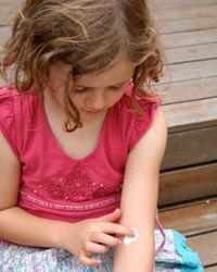 A young girl applying lotion to her skin