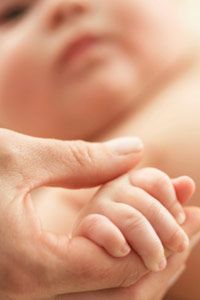 A tender moment: mother holding her baby's hand.