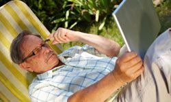 elderly man working on a laptop in an outdoor setting