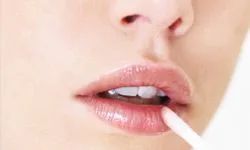 Close-up of a young woman applying lip gloss
