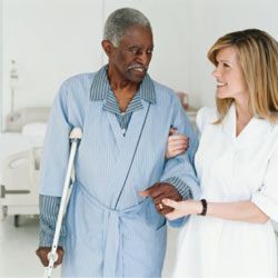 nurse assisting an elderly man walking with crutches