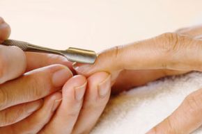 A woman getting a manicure with her cuticles gently pushed back.