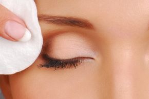 A woman cleaning her face with cotton pads during a cosmetic routine.