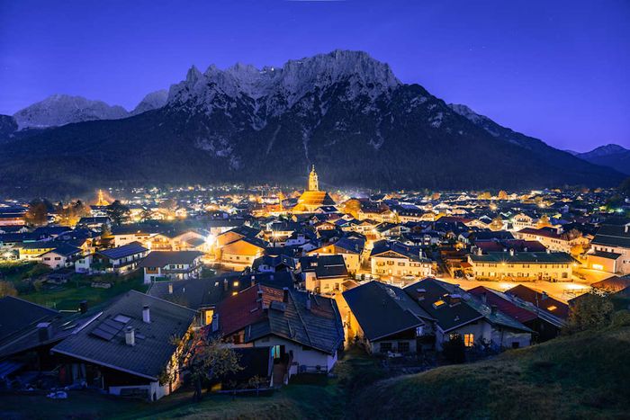 A breathtaking nighttime view of Mittenwald, with illuminated streets and the majestic Karwendelgebirge mountains in the background