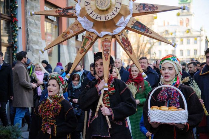 Ukrainians singing carols while carrying a large...