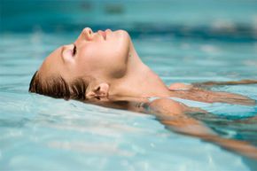 A serene image of a woman floating gracefully in a swimming pool.