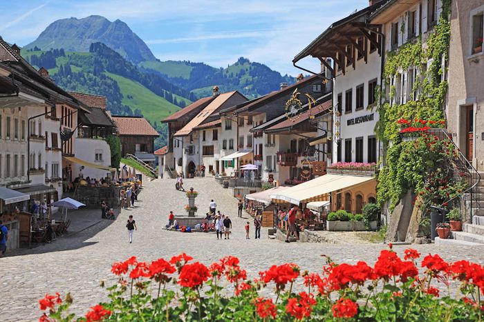 A street in Gruyères, Switzerland, lined with houses and framed by mountain vistas