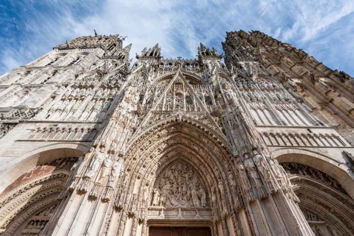 The intricately sculpted western facade of the Gothic-style Rouen Cathedral.