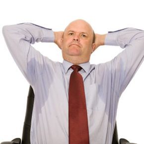 A man visibly struggling with heavy sweat marks on his clothing.