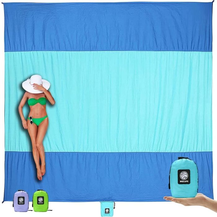 A person sitting on a Wekapo Sand-Free Beach Blanket against a white background.
