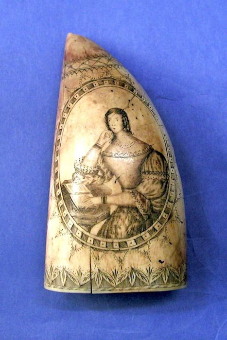 A 19th-century piece of scrimshaw on a sperm whale tooth shows a Victorian lady at a desk with an open book, demonstrating the skill and artistry of this folk tradition.