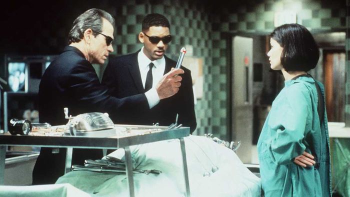 1997: K (Jones) and J (Smith) prepare to neuralyze Deputy Med over the body of an alien in disguise.