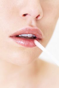 Close-up of a young woman applying lip gloss