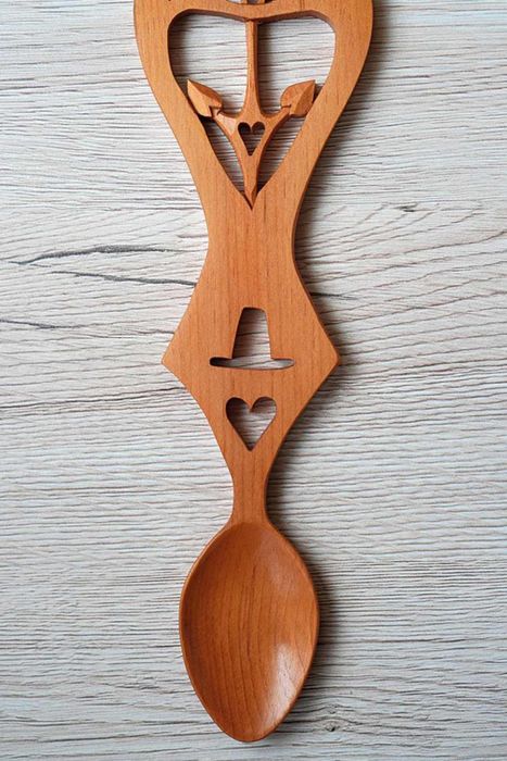 An intricately carved wooden spoon featuring symbols of love in the handle