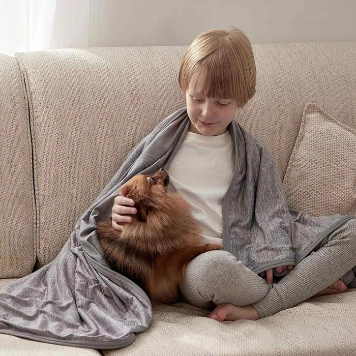 A child and dog cozying up under a Bedsure Cooling Summer Blanket on a couch