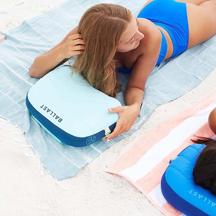 A person relaxing outdoors with a Ballast Inflatable Beach Pillow