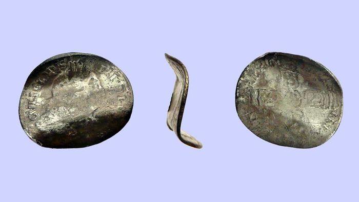 Three views of a silver sixpence coin from the reign of William III (1694-1702), bent into an ‘S’ shape to create a love token.
