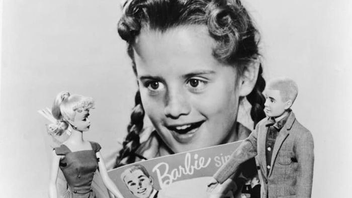 A child playing with Barbie and Ken dolls in 1961.