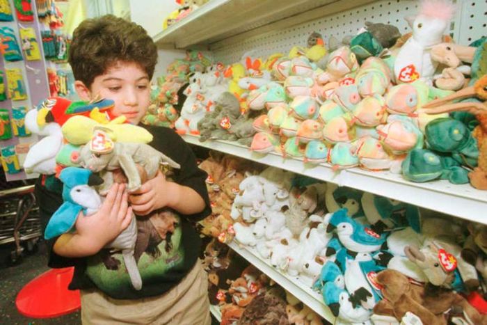 A boy in a toy store carrying an armful of Beanie Babies.