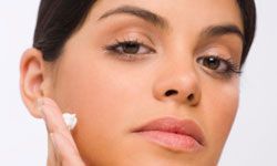 A woman massaging face cream into her skin.