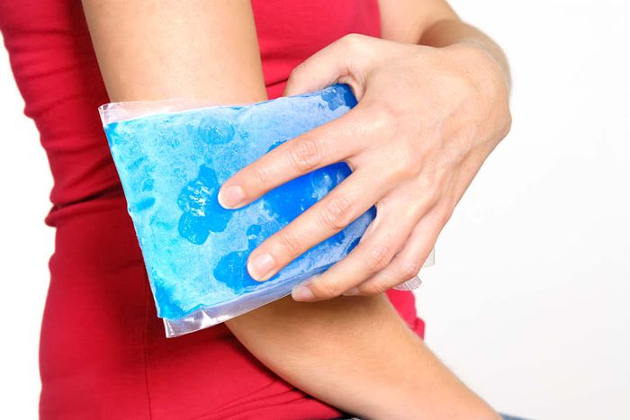 A woman in a red shirt holding an ice pack to her elbow