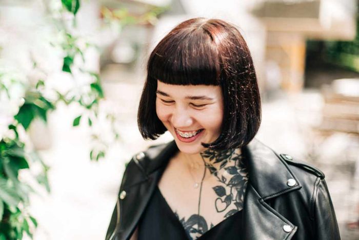 A woman with short hair and tattoos wearing a leather jacket