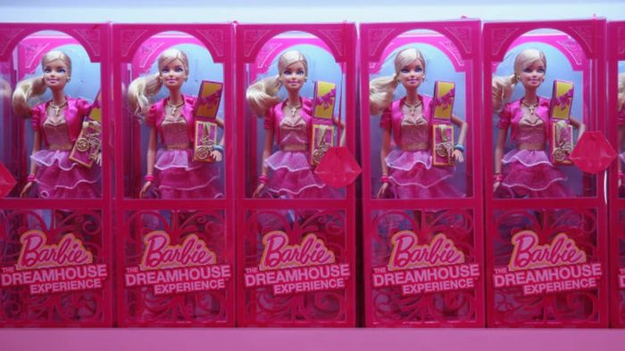 A lineup of Barbie dolls in pink packaging
