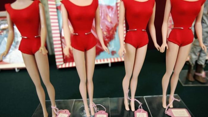 Four Barbie dolls in red swimsuits showcasing their tiny waists