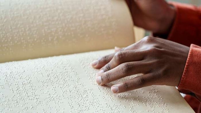A woman engrossed in reading a book written in braille.