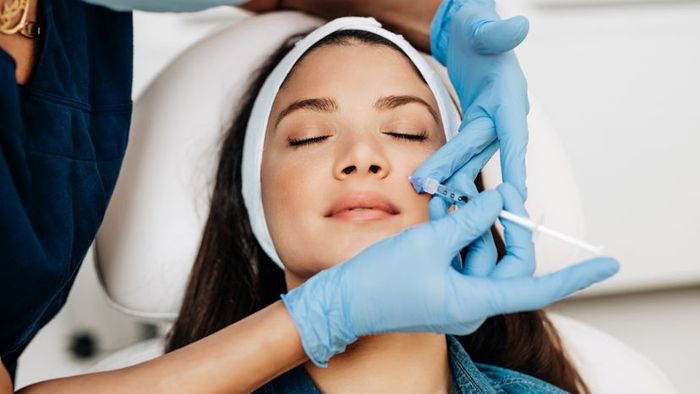 A youthful woman receives facial injections for rejuvenation at a beauty clinic