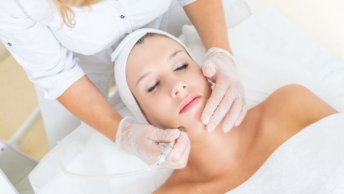A young woman undergoing a facial microdermabrasion procedure for smoother skin.