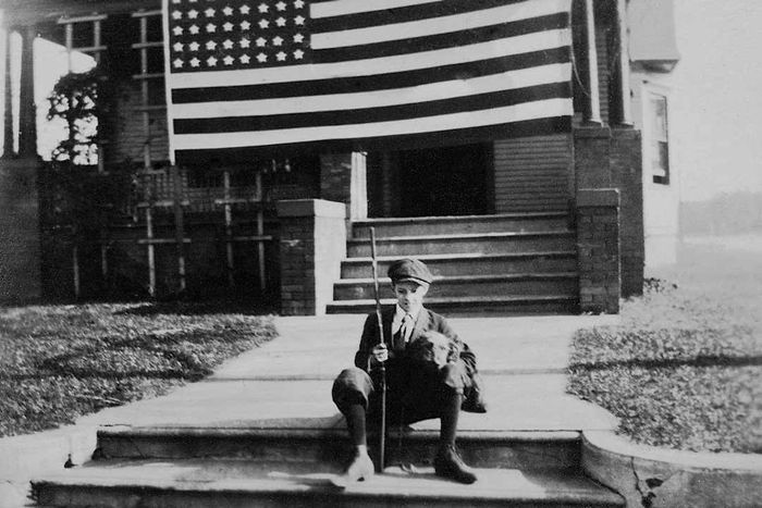 A young boy stands in front of his home on Armistice Day, November 11, 1918.