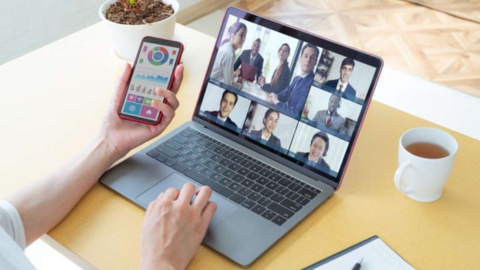 A person simultaneously uses a smartphone and a laptop