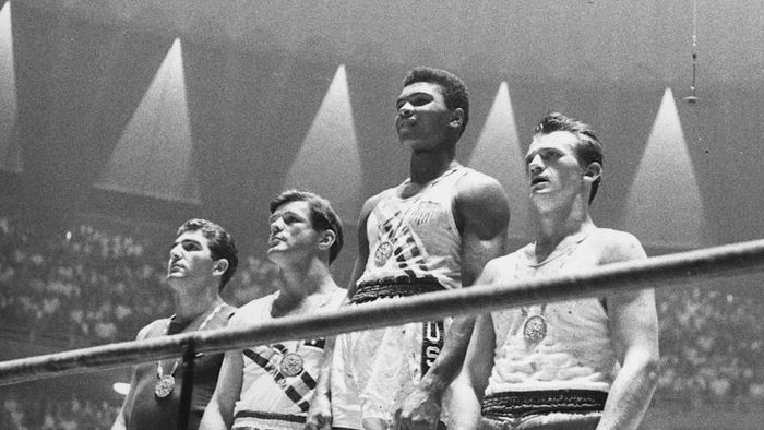 A photograph features Anthony Madigan, Giulio Saraudi, Muhammad Ali, and Zbigniew Pietrzykowski
