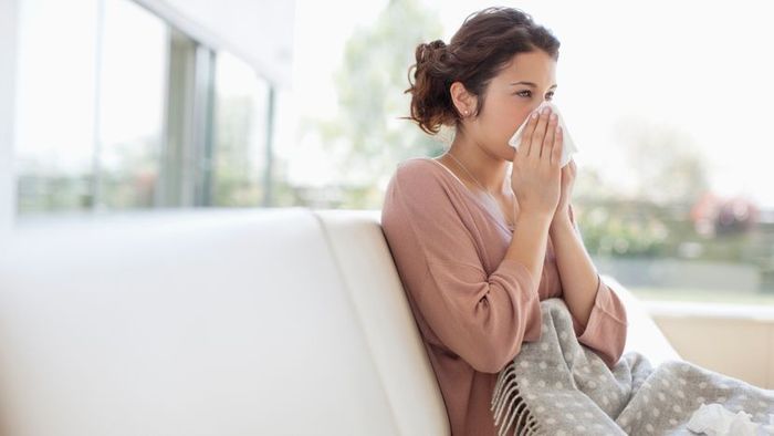 A woman feeling unwell, resting on a couch.