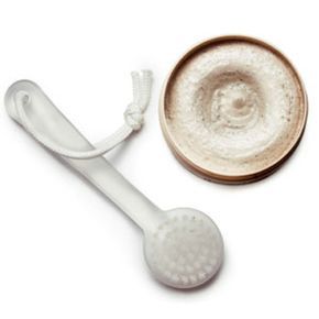 A facial massaging brush paired with a honey scrub, isolated on a white background
