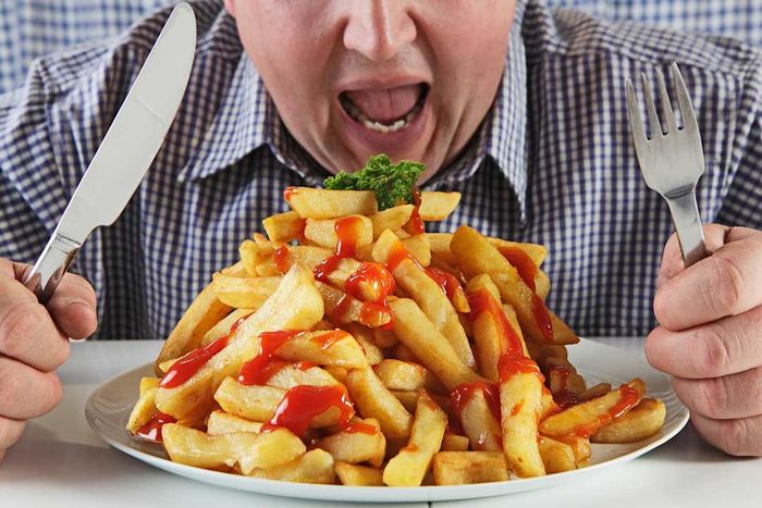 Man with mouth wide open, eyeing fries