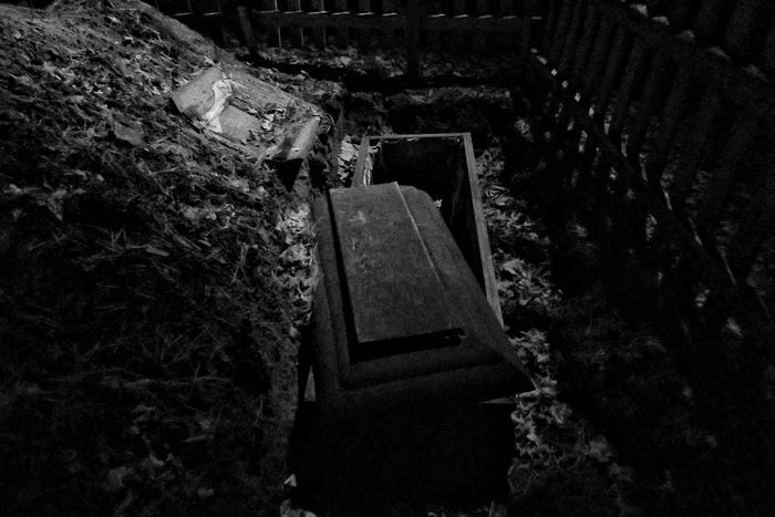 A black-and-white image of an open coffin in a field